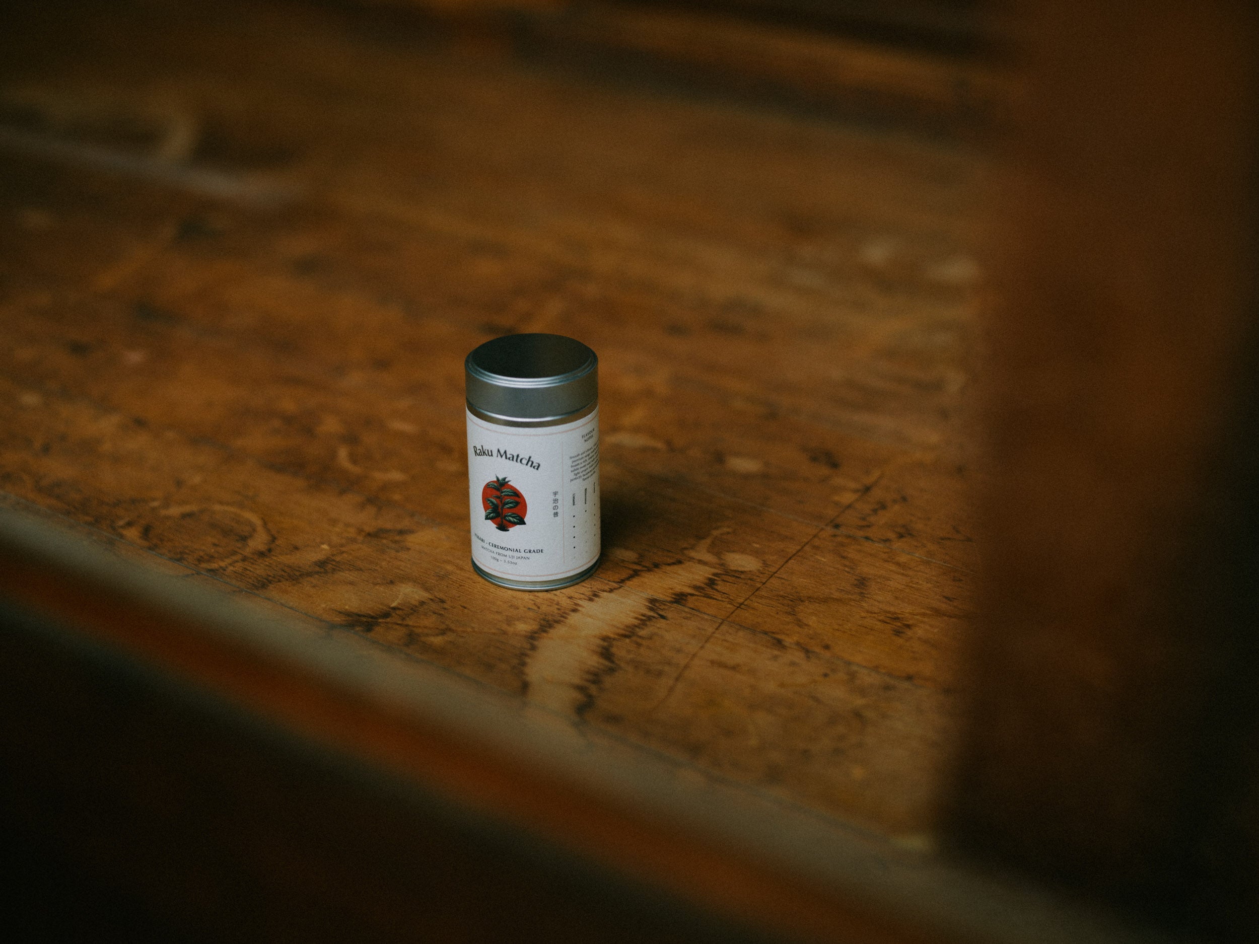 A tin of Raku Matcha on an old wooden table